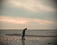 lonley man wlaking on a beach